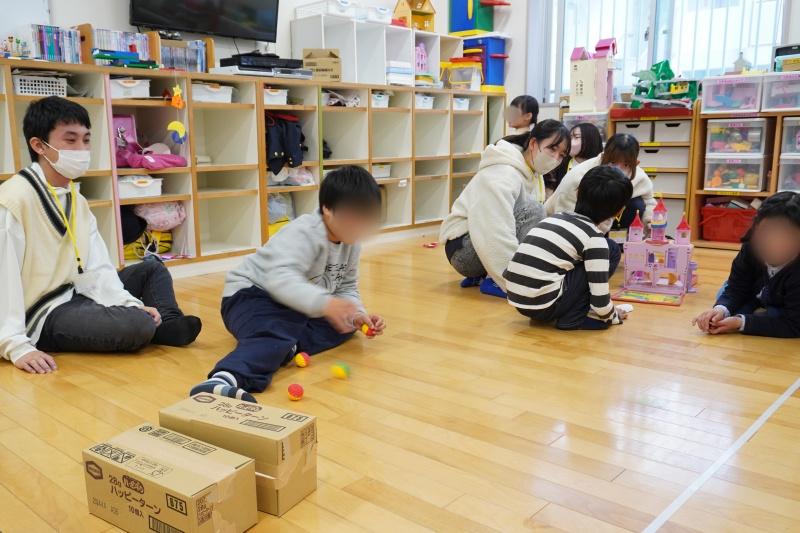 学校から帰った子どもたちと一緒に遊ぶ学生ぷちボランティアセンター（ぷちぼら）のスタッフ1